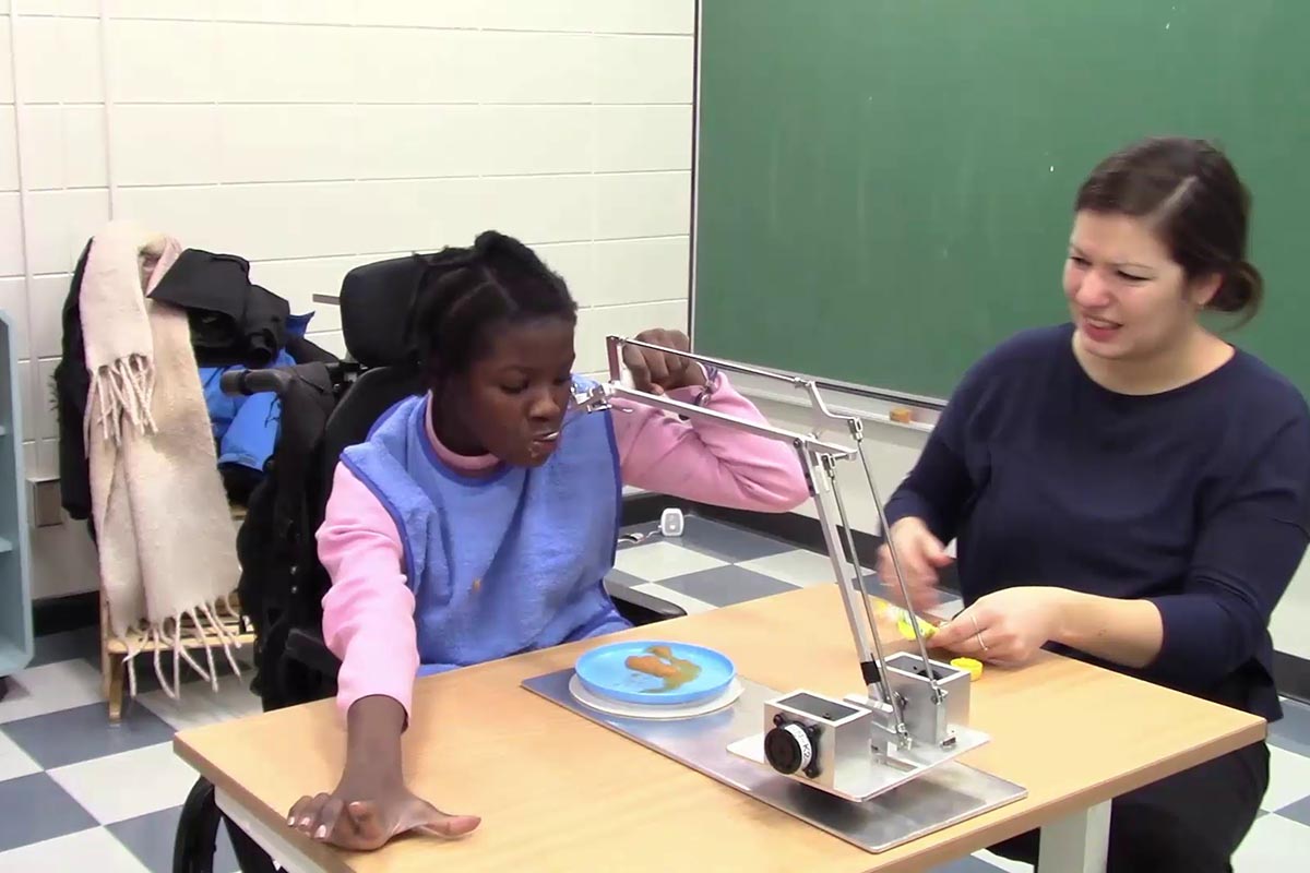 Une jeune fille vivant avec un handicap utilise un support d'aide à l'alimentation.